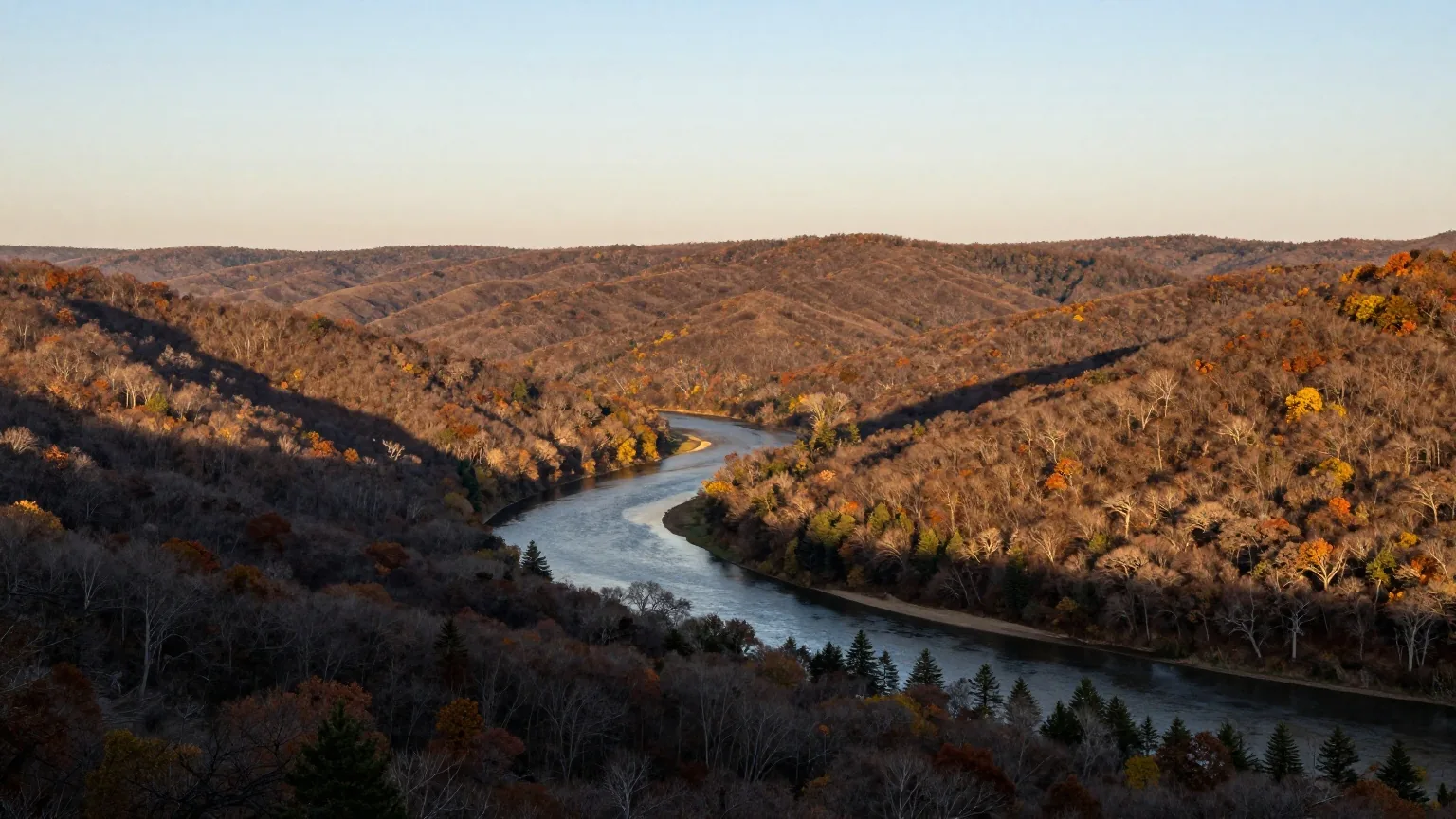 Bewaldete Hügelketten im Südosten Oklahomas im späten Nachmittagslicht, im Tal ein Fluss zwischen Eichen und Kiefern